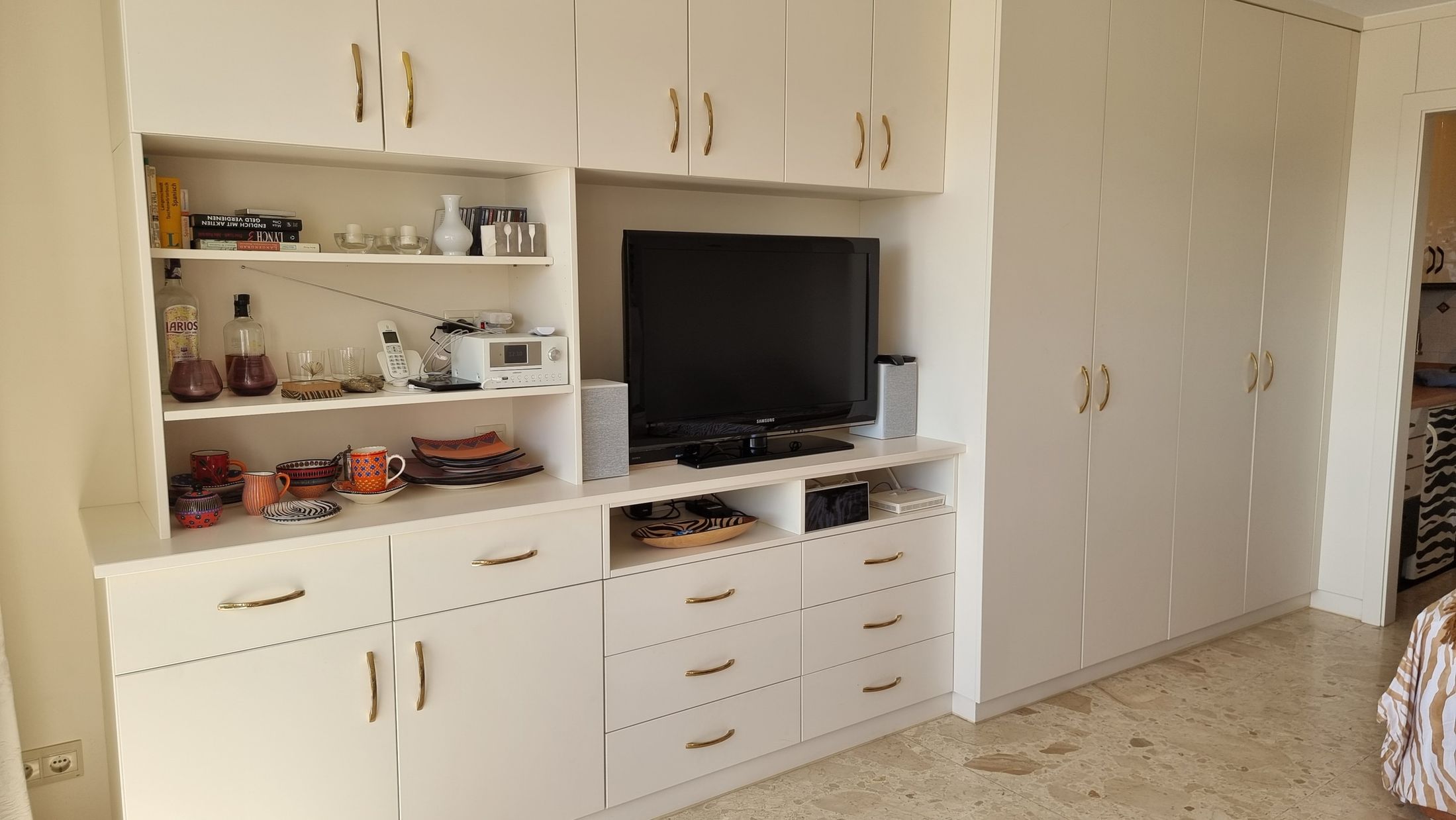 Helle Schrankwand mit Fernseher, offenen Regalen und Schubladen