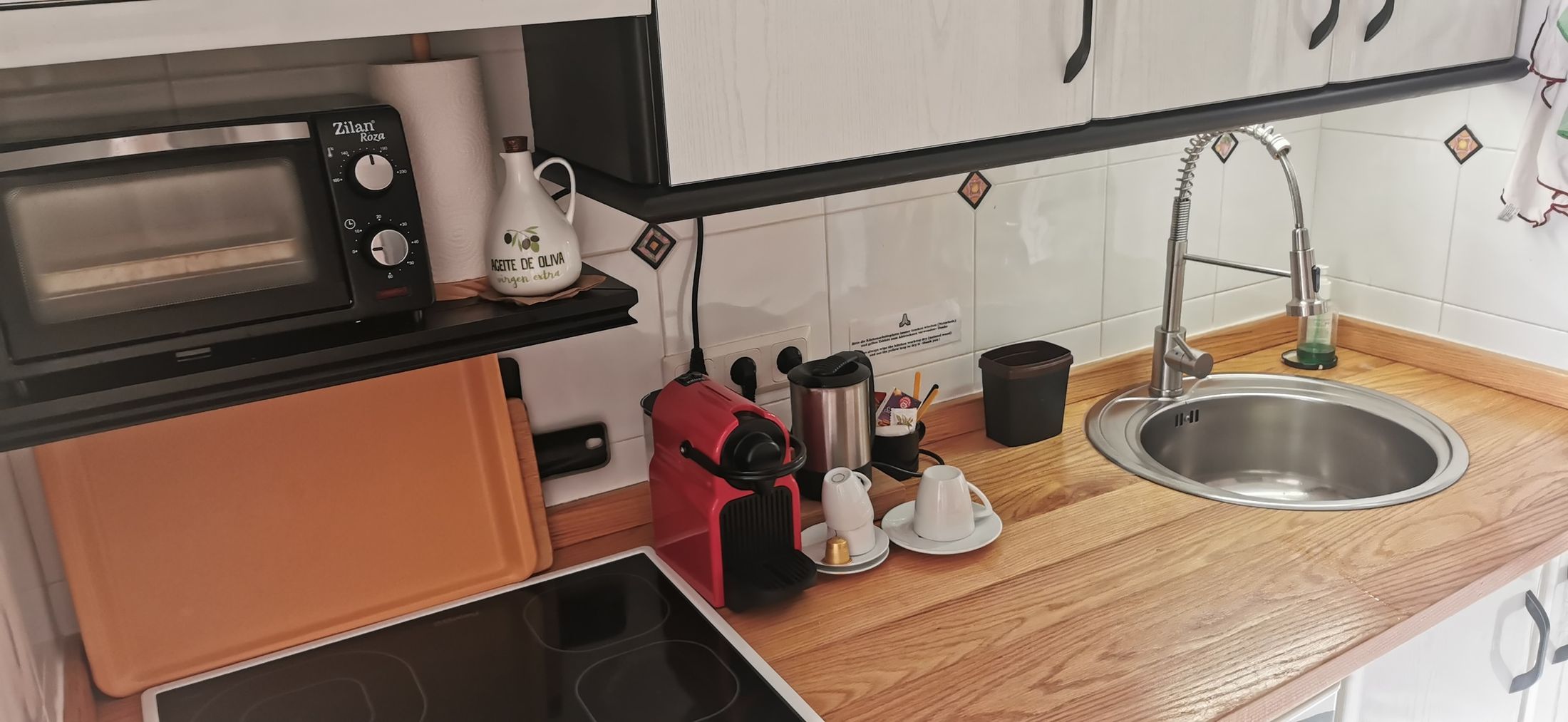 Arbeitsfläche der Küche mit Spüle, Kochfeld, Kaffeemaschine und kleinem Backofen