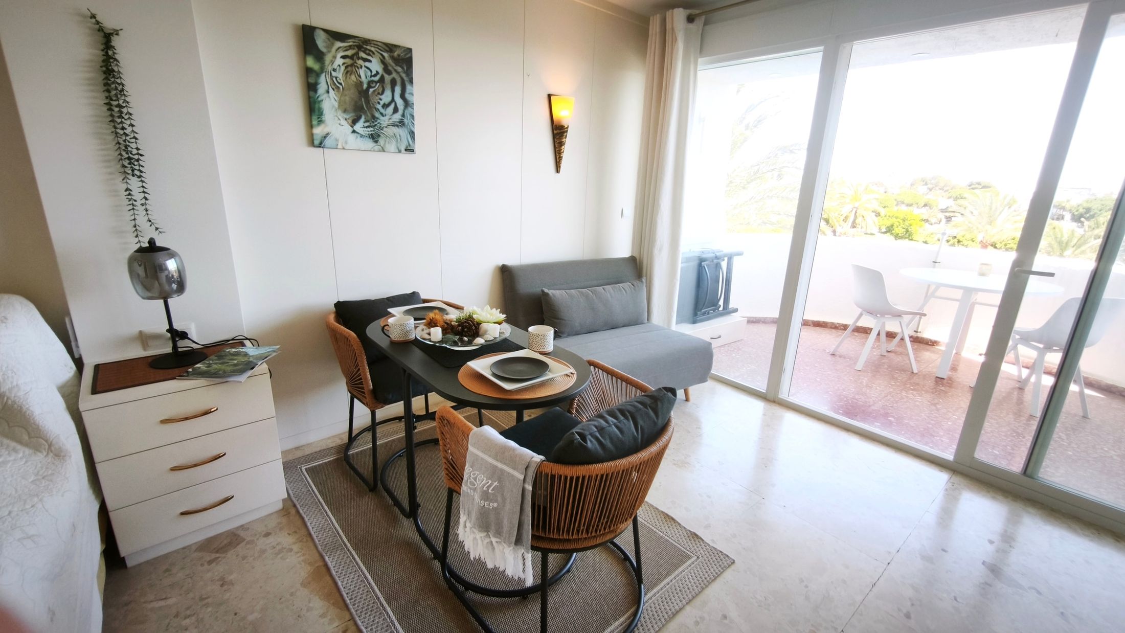 Esstisch, Korbstühle und grauer Sessel neben der offenen Schiebetür zur Terrasse