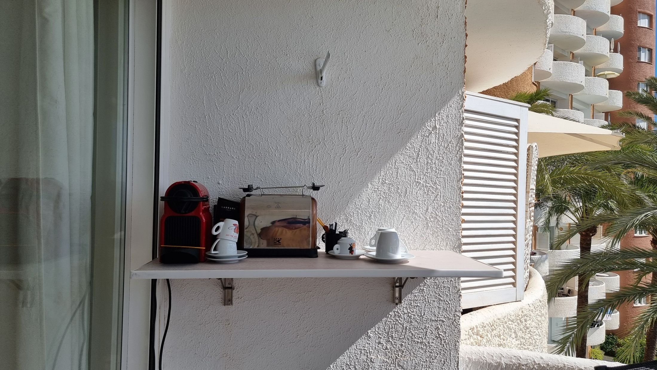 Kleine Ablage mit Kaffeemaschine an der Terrassenwand neben der Schiebetür